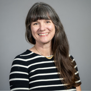 MS in Information Design and Strategy faculty member Lauren Liss headshot against a professional neutral background. She wears a striped shirt and necklace.