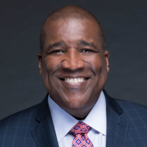 Curt Menefee wears suit and big smile for a headshot. He is the keynotes speaker for SPS Convocation 2025.