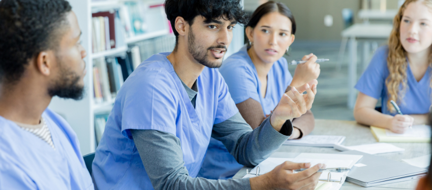 pre-medicine post-baccalaureate students gather around a table during a Proseminar Course.